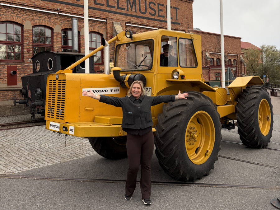 En kvinna lyfter armarna i glädje framför den klassiska traktorn Volvo BM T 873 Lantbruks-Lisa utanför Munktellmuseet.