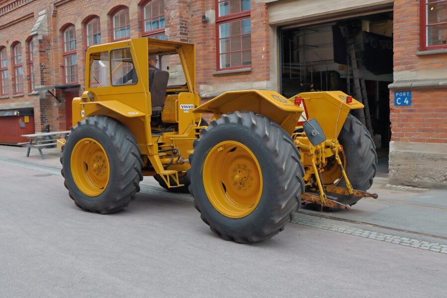 En man sitter i hytten på en Volvo BM T 873 Lantbruks-Lisa utanför Munktellmuseet och förbereder sig för att köra in genom porten.
