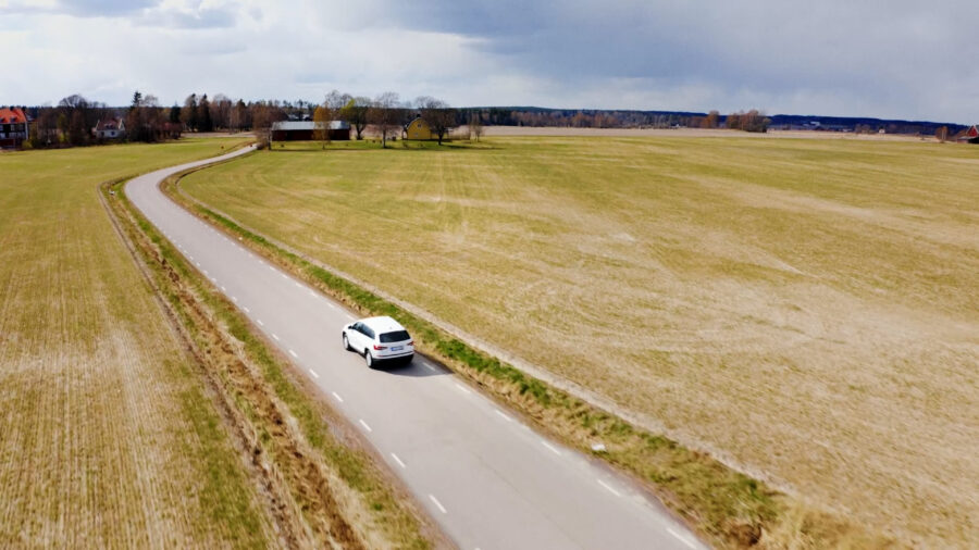 En bild som kör på en väg mellan åkrar